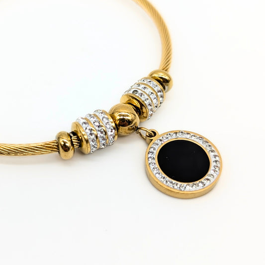 Close-up of black enamel charm with crystal frame on gold cable bracelet