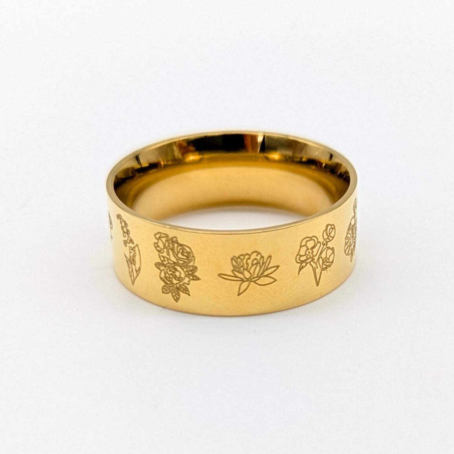 Gold ring with floral engravings on a white background