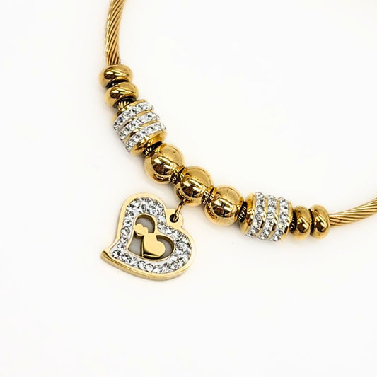 Close-up of crystal heart charm with gold cutout center on cable bracelet