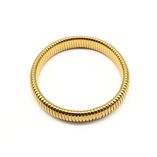 Close-up of flexible gold bangle on white background