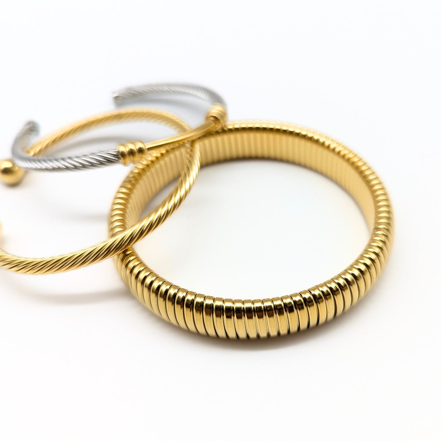 Close-up of gold and silver bangle cuff bracelets on white background