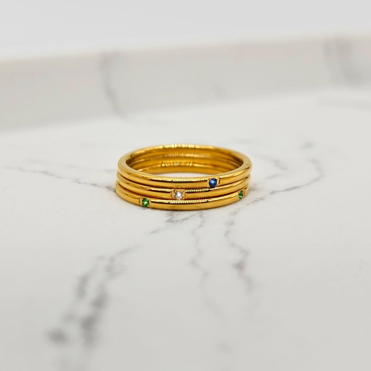 Gold stacking ring set with blue, green, and clear gemstones