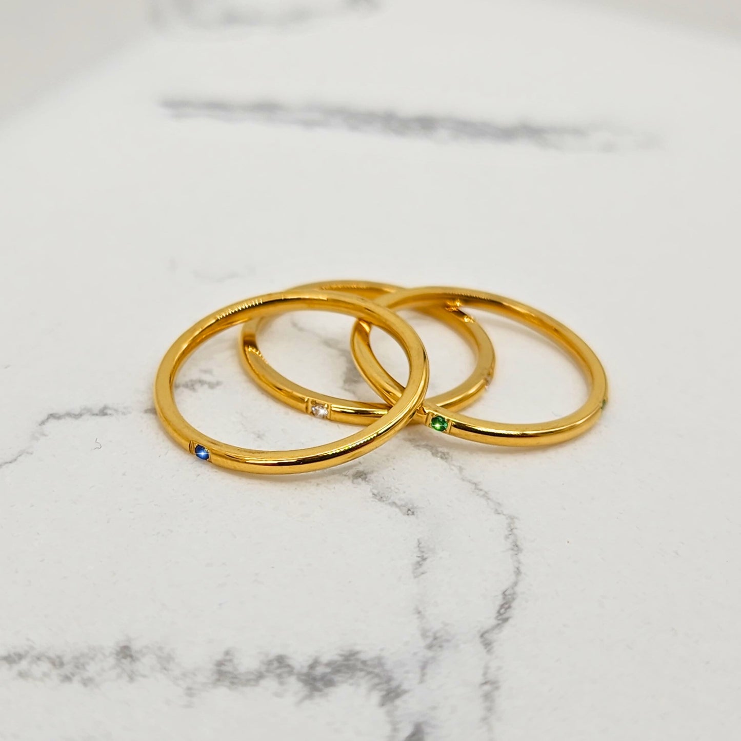 Slim gold bands with colorful gemstones displayed separately