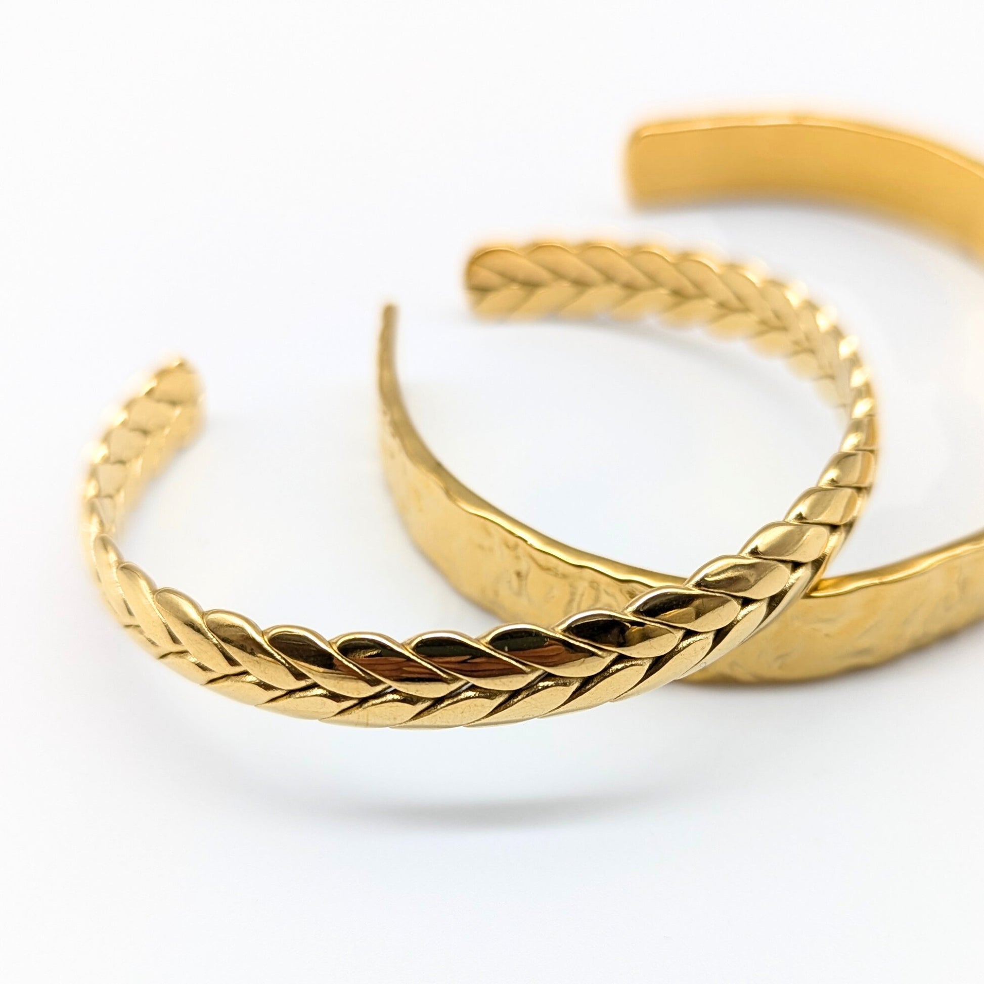 Two gold braided bracelets on a white background