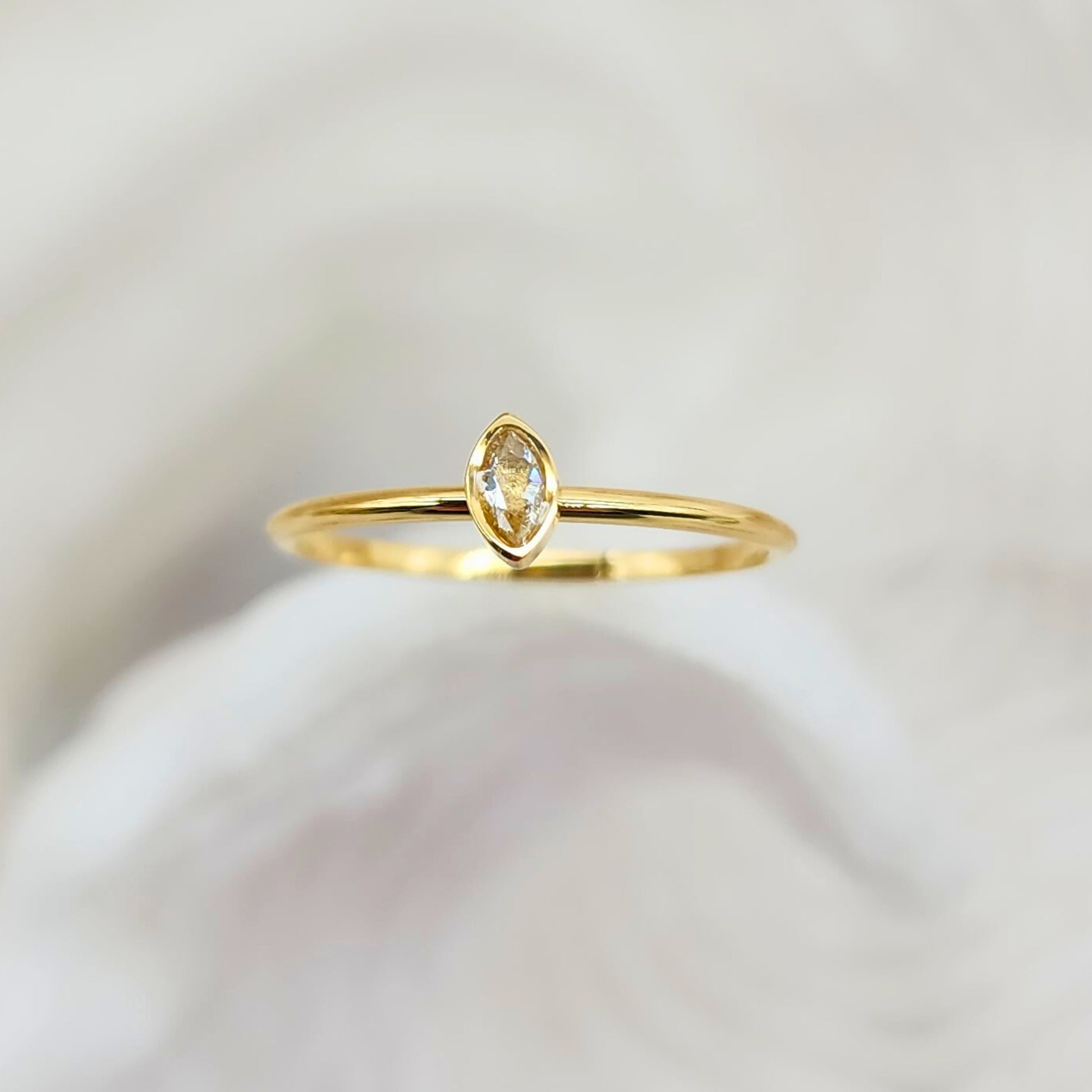 Minimalist marquise solitaire ring with eye-shaped bezel setting on thin gold band, front view