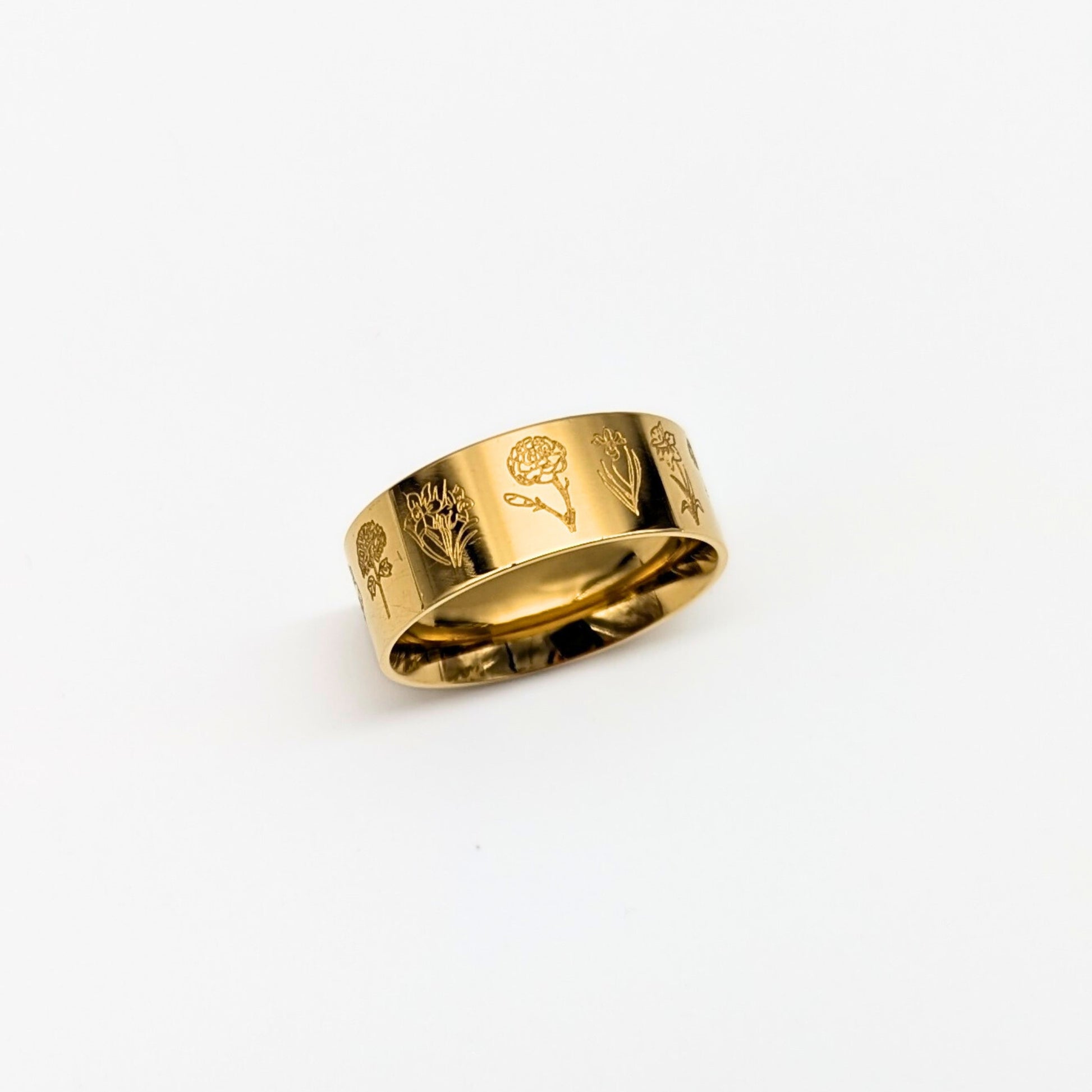 Gold ring with engraved floral designs on a white background