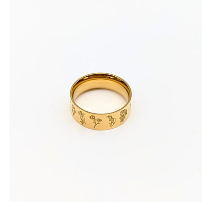 Gold ring with engraved floral designs on a white background