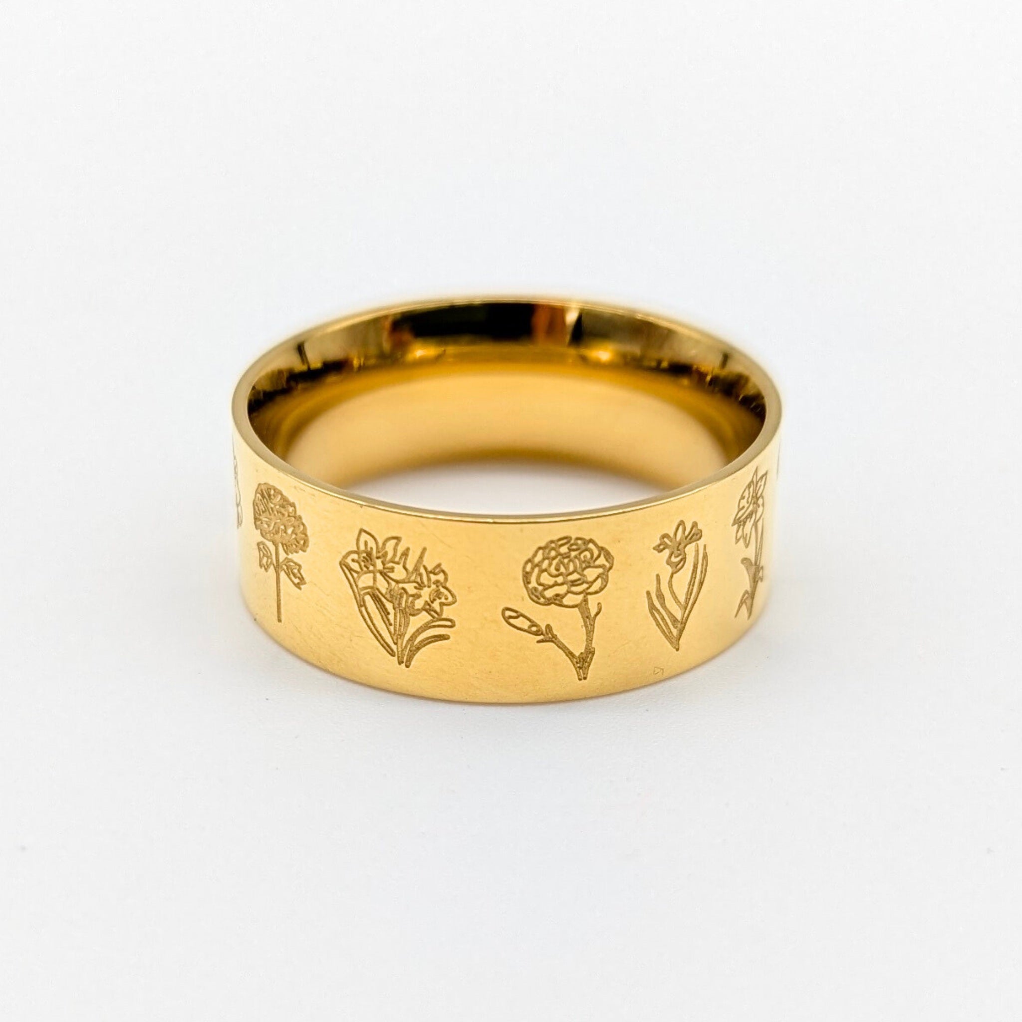 Gold ring with floral engravings on a white background