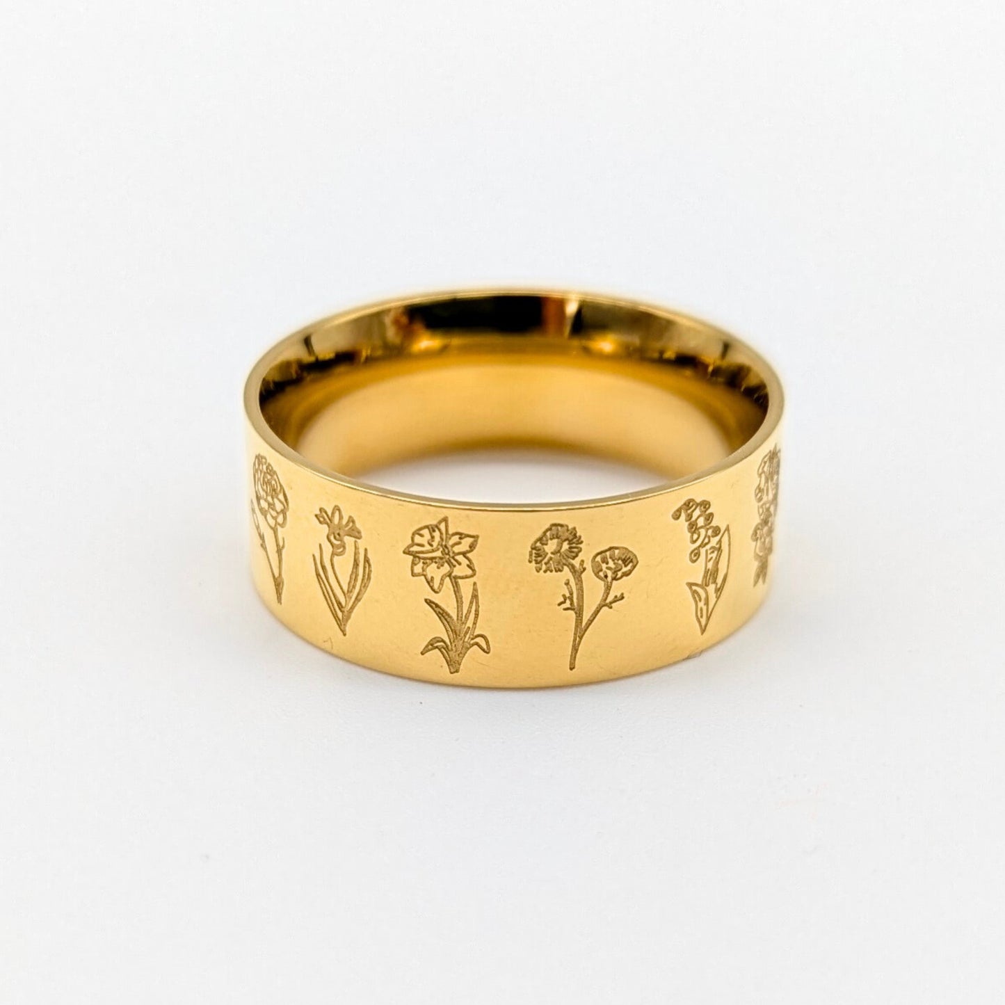 Gold ring with engraved floral designs on a white background