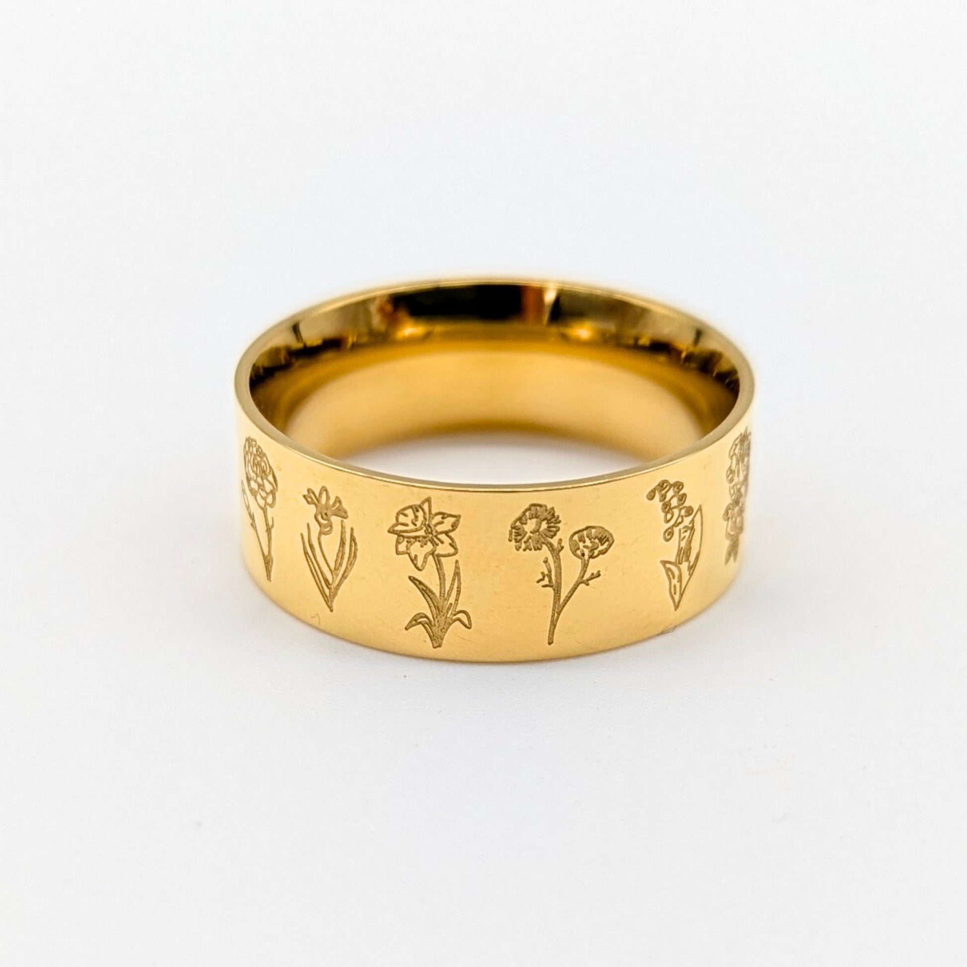 Gold ring with engraved floral designs on a white background