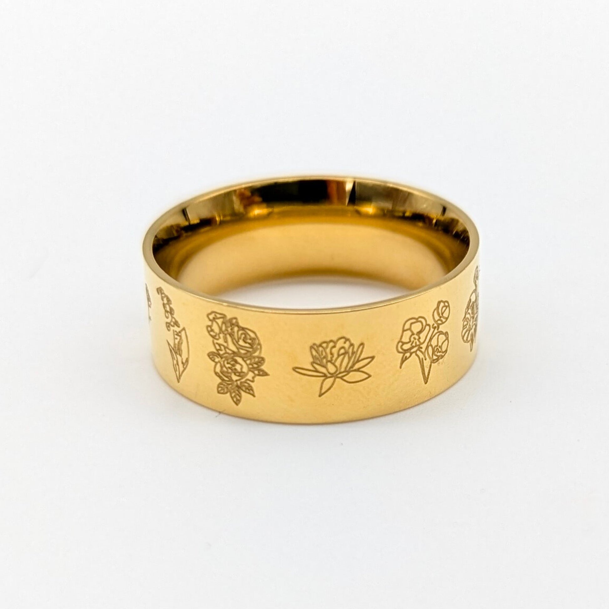 Gold ring with floral engravings on a white background