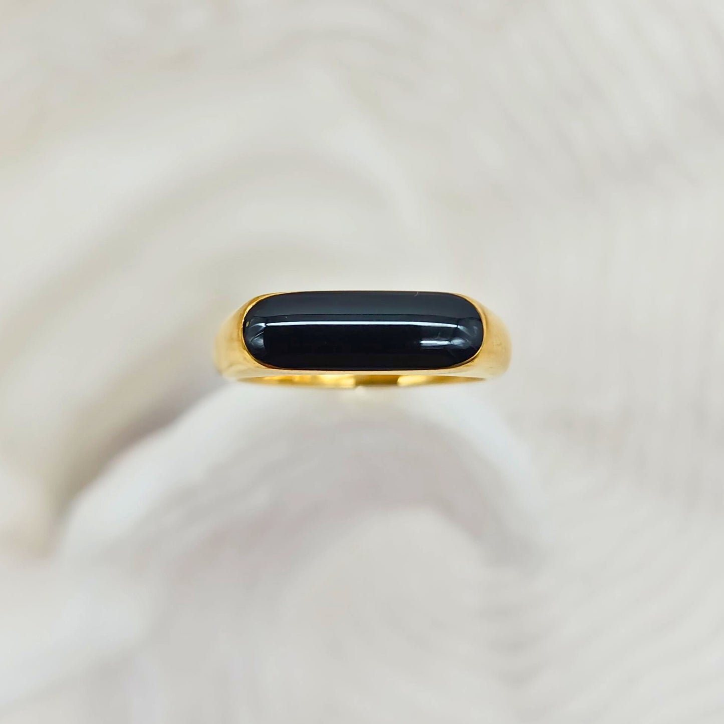 Minimalist gold ring with smooth rounded black center, front view