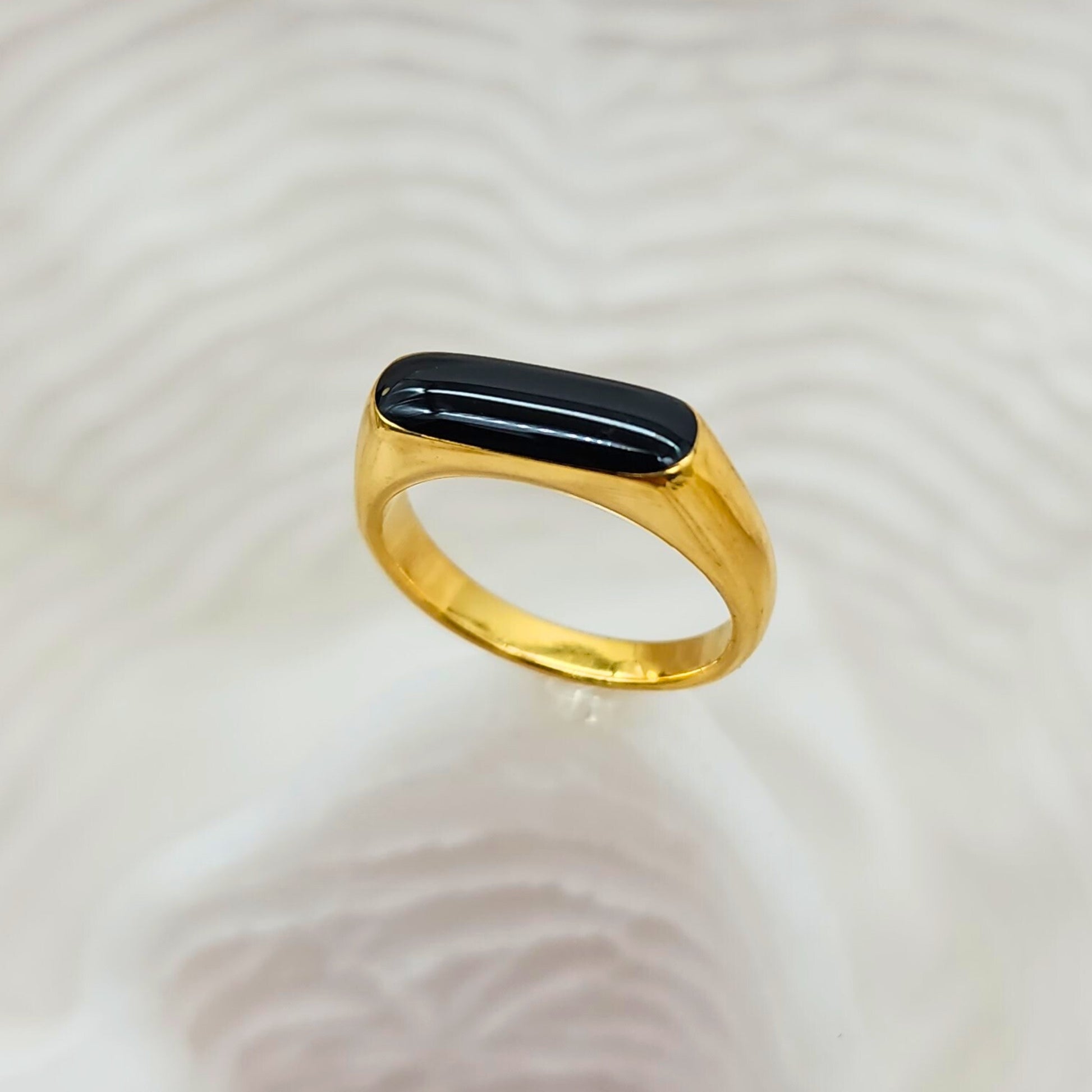 Gold domed statement ring with polished black inlay on textured background