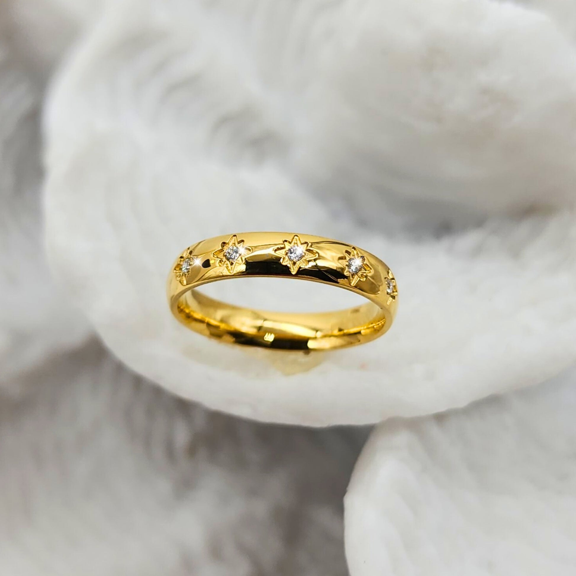 Gold ring with star designs on a soft white background