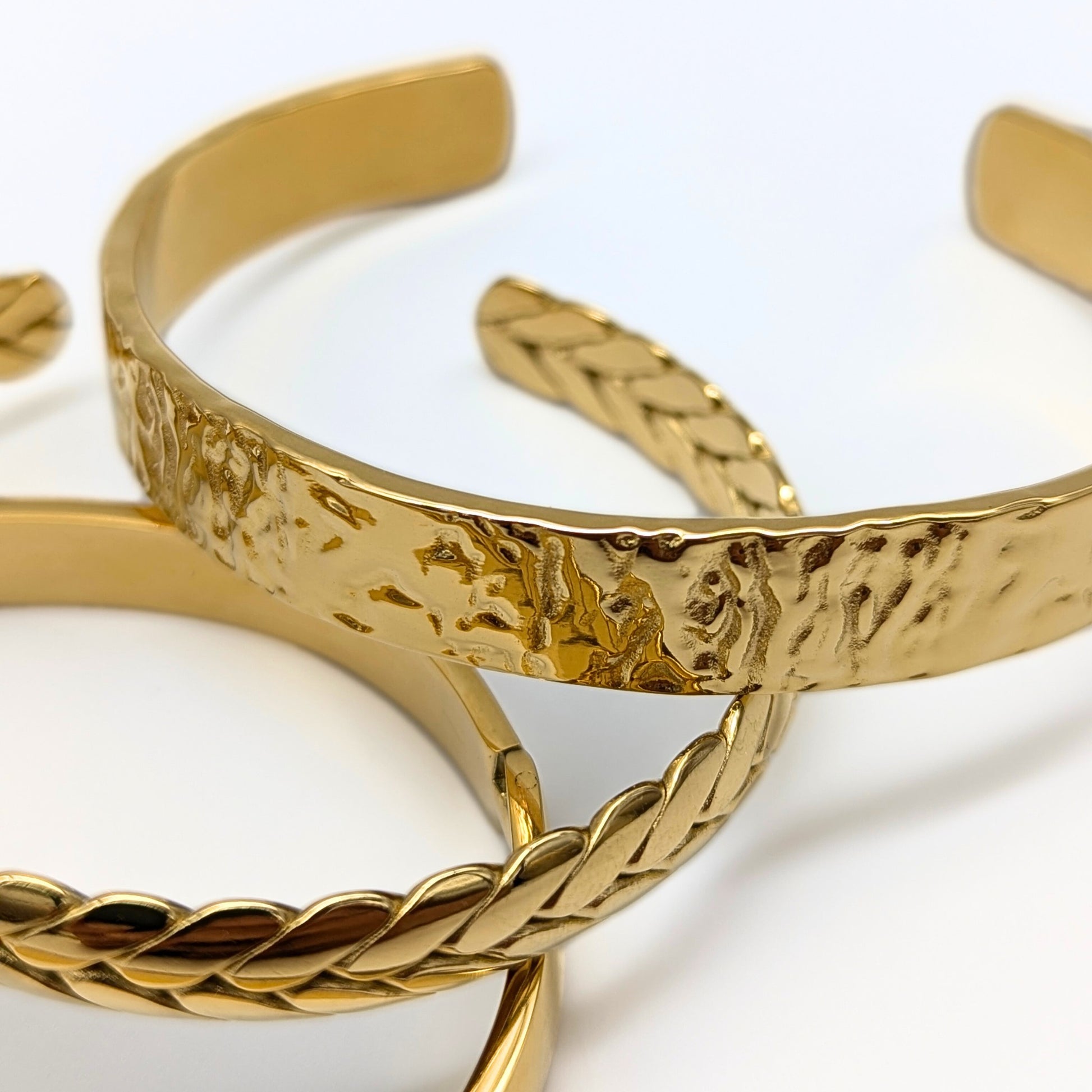 Gold bangles with textured design on a white background