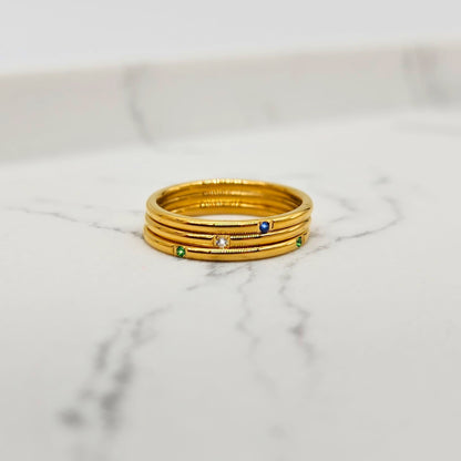Gold stacking ring set with blue, green, and clear gemstones